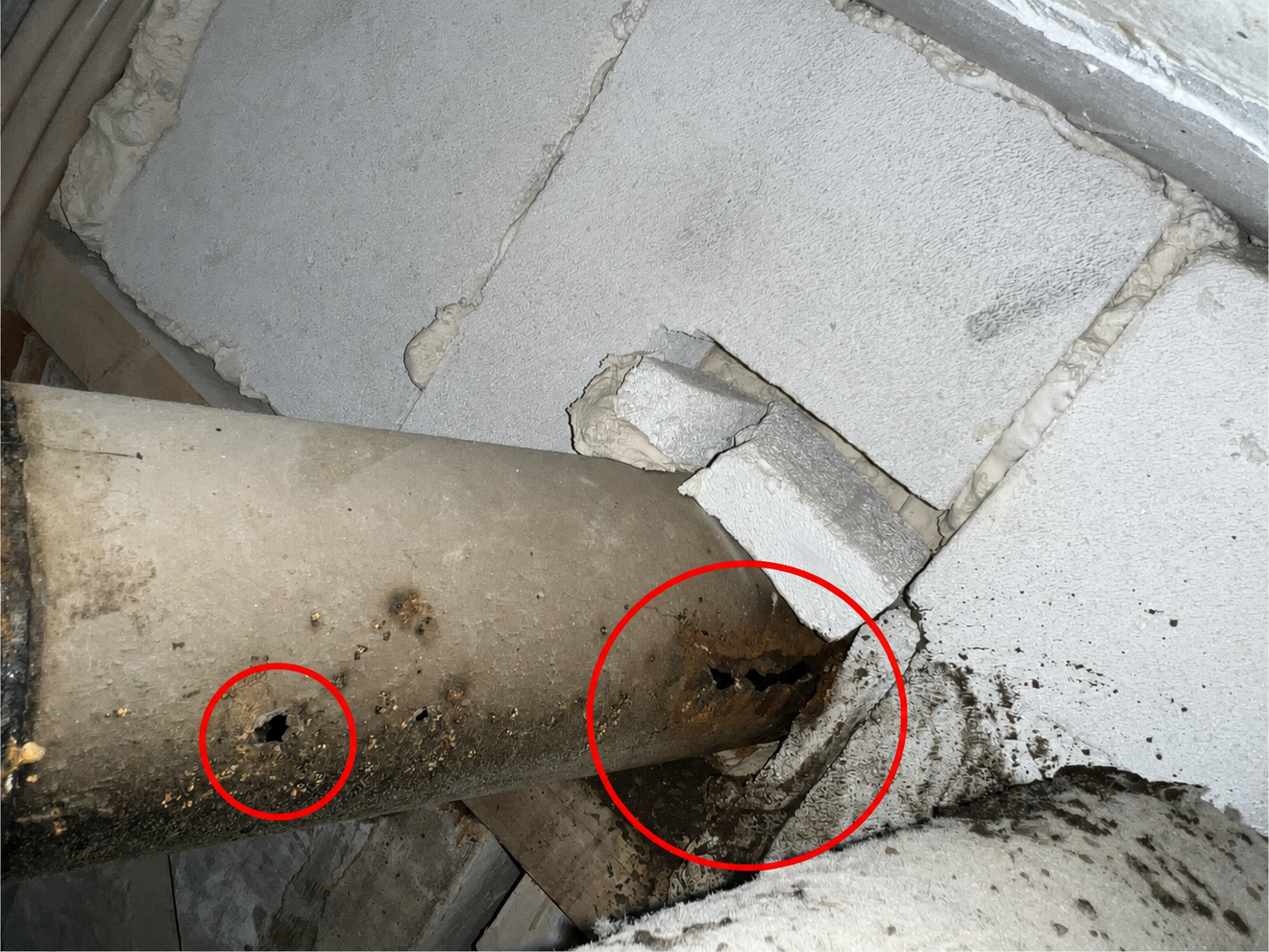Detaljbild som visar kraftig korrosion, genomrostning och hål längs rörstammen före åtgärd.